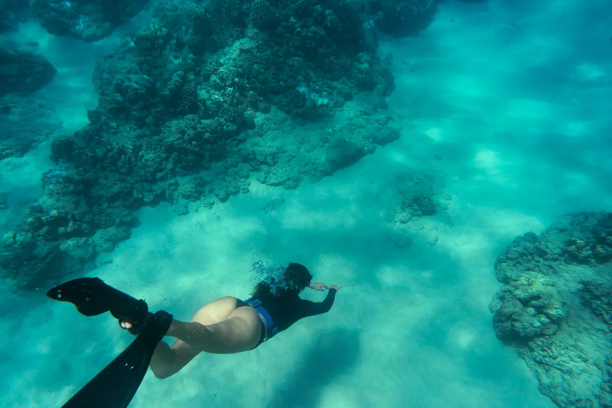 Snorkeller swimming over rocks in clear turquoise water
